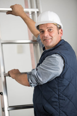 portrait of worker with hands on rungs of a ladder