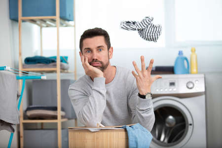 bored husband man doing laundry at homeの写真素材