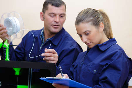 male and female technicians working with 3d printerの写真素材