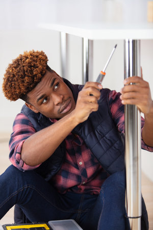handsome young man using screwdriver for fixing table