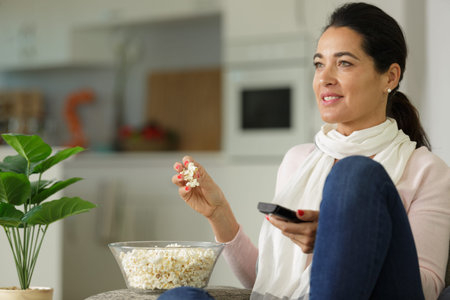 happy woman eating popcorn while watching television