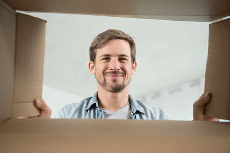 portrait of smiling young man looking into boxの写真素材