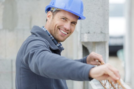 happy man builder looking at camera while installing metal beamsの写真素材