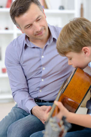 young boy learning to play a guitarの写真素材