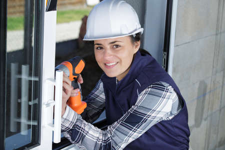 female construction worker using power tool on windowの写真素材