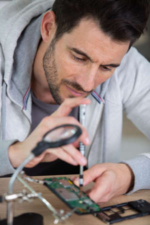 male repair technician soldering electrical partsの写真素材
