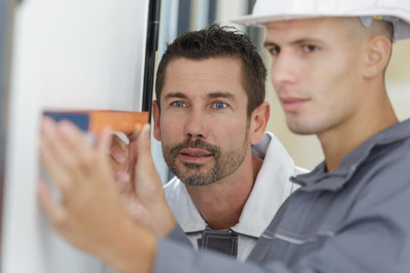 two men using spirit level on wall
