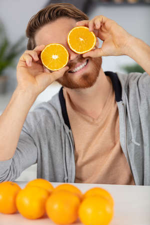 happy young man having fun with orangesの写真素材