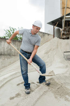 man takes a shovel of sandの写真素材