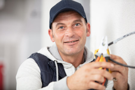 electrician wiring up a junction box holding cable cutters