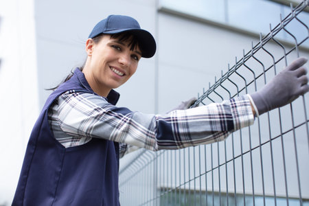 smiling woman is holding a fence