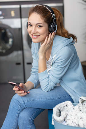 woman in laundrette listening to music to pass the timeの写真素材
