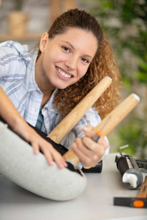 woman screwing leg back on to a stoolの写真素材