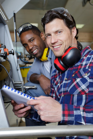 two engineers using a machine in a factory