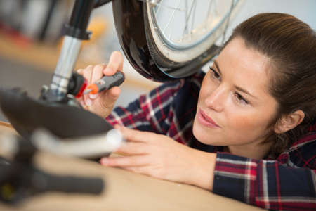 woman bicycle engineer is repairing a bike in the workshopの写真素材