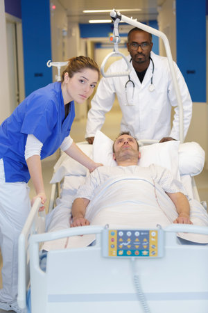 group of doctors carrying man patient on hospital gurney