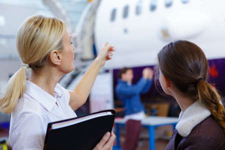 pretty pilot woman pointing at airplaneの写真素材