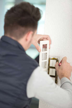 electrician installs lighting switch in the wallの写真素材