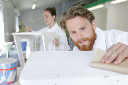 portrait of focused modern carpenter sanding woodの写真素材