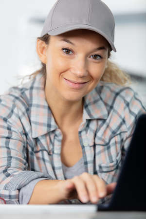 female manual worker wearing a cap using a laptopの写真素材