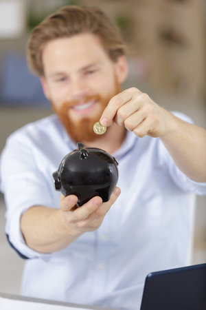 man putting coin in piggy bank