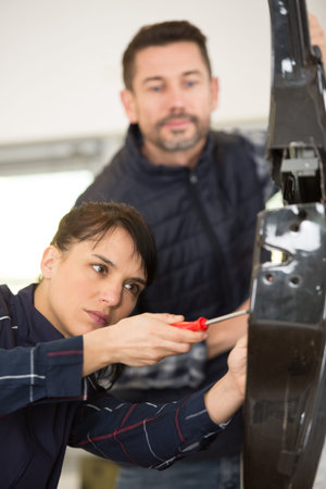 male and female panelbeaters working on a car door