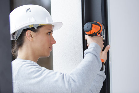 woman with a screwdriver tightens the windwo fixingsの写真素材