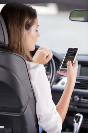 woman holding a smart-phone inside a car