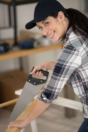 a female carpenter sawing woodの写真素材