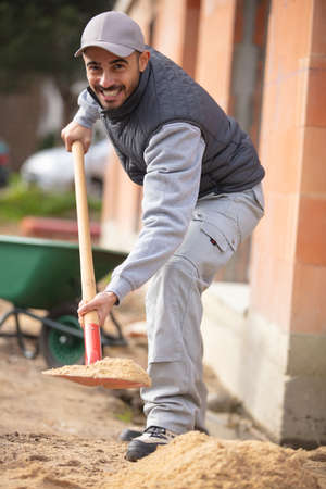 tradesman holding a shovel at construction siteの写真素材