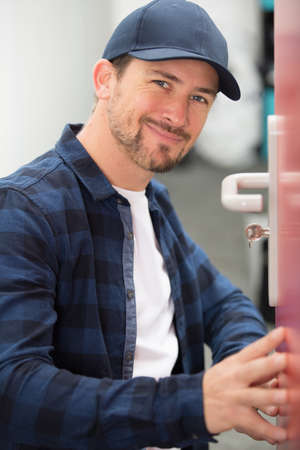 man fixing a door handle with screwdriverの写真素材