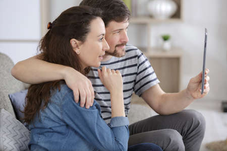 young couple with tablet on sofa indoorの写真素材
