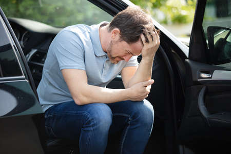sad driver after car accident holding hand on his headの写真素材