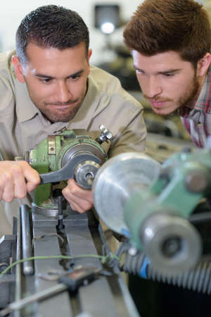 mechanic showing parts of an engine to apprenticesの写真素材