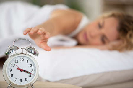 woman turning off the alarm clockの写真素材