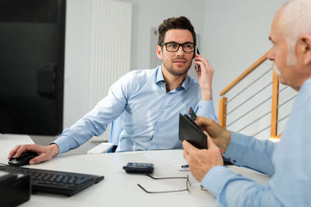man using phone while having a meeting with a seniorの写真素材