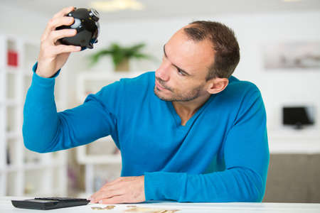 man looking at his empty piggybankの写真素材