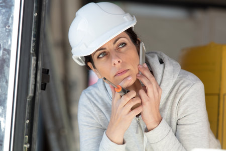 contemplative female builder with telephone to her earの写真素材