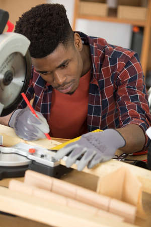young man construction carpenter working with electric sawの写真素材