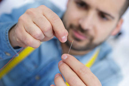 closeup of tailor threading needleの写真素材