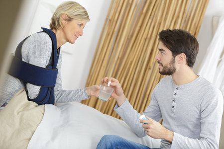 recovering lady with home help giving pillsの写真素材
