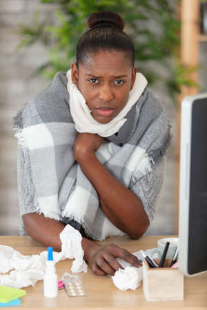 sick businesswoman sitting at desk in the officeの写真素材
