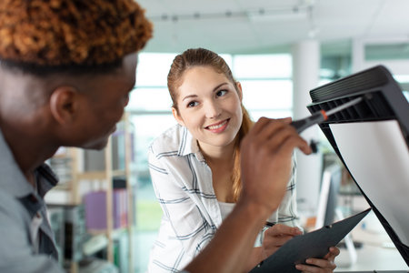 professional repair printer in office explaining to woman worker