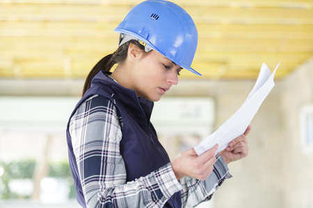 female builder looking at paperwork on siteの写真素材