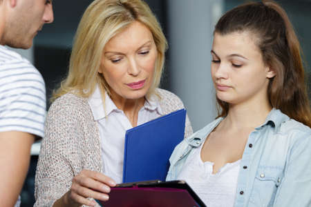 mature female teacher helping teenage studentの写真素材