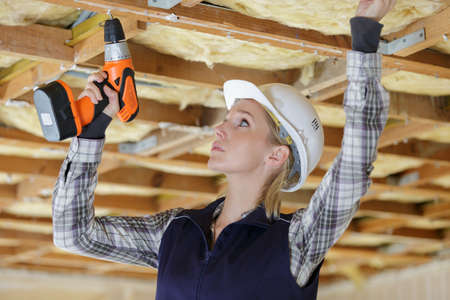 woman using drill on indoor construction siteの写真素材