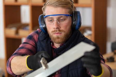 serious young male carpenter working with woodの写真素材