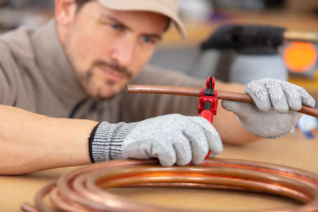 industrial plumber cutting a copper pipeの写真素材