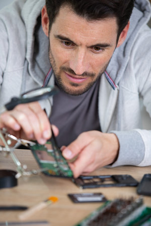 man repairing broken smartphone in workshop