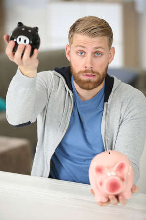 man holding two different sized piggybanksの写真素材